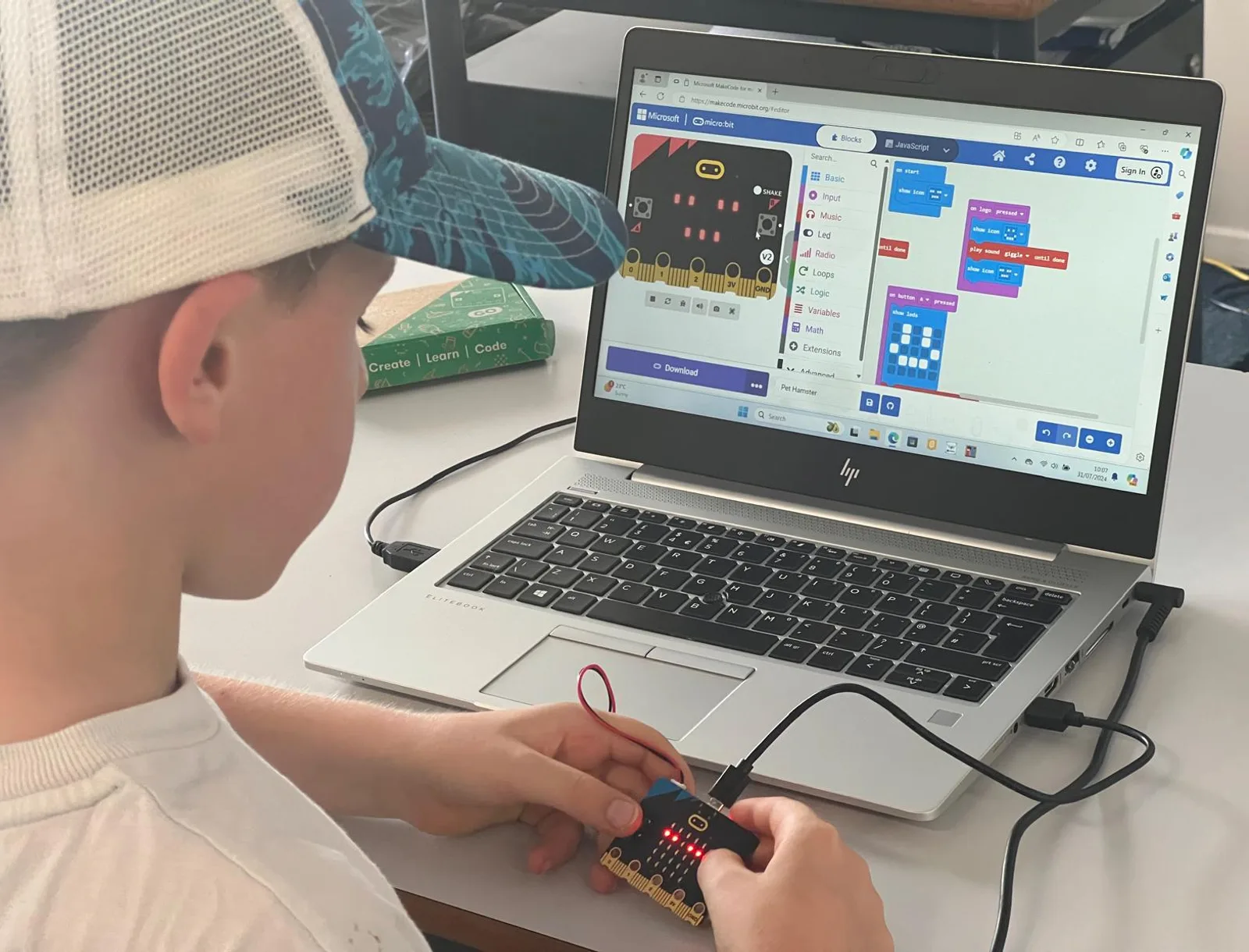 A child programming a micro:bit on a laptop, with block code on screen